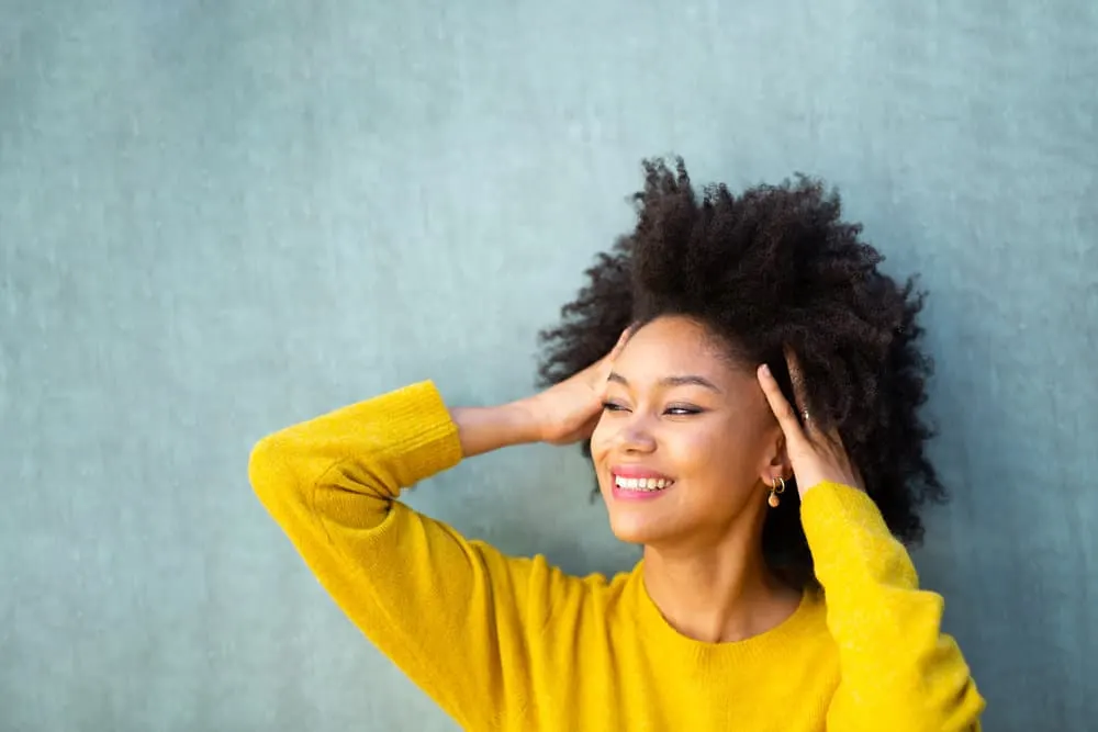 A happy black lady with sparkling white teeth wearing her coily hair in a wash n' go hairdo.