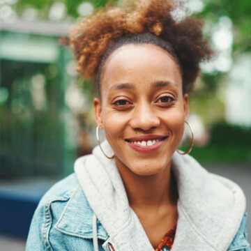 A young African American female with very dark hair wearing a bleached hair color in an updo ponytail style.