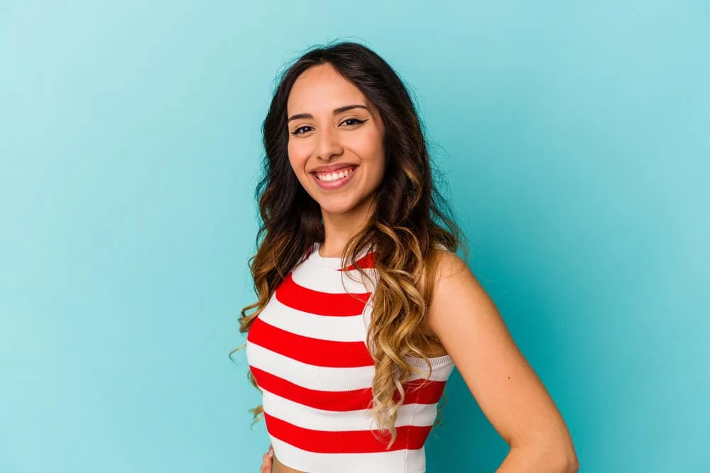 Hispanic female with naturally dark hair that underwent a chemical process to create lightened hair tips.