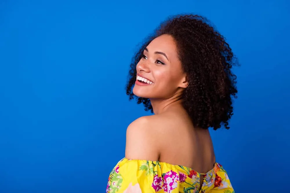 Young black girl with frizz-free hair after receiving a cold keratin protein treatment on wet hair to avoid heat damage.