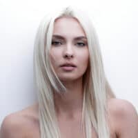 A cute young white girl wearing her platinum hair blonde after having toned it with purple shampoo.