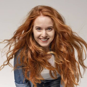 A cute red head with 2B hair strands using the Curly Girl method for a proper hair care routine for her wavy strands.