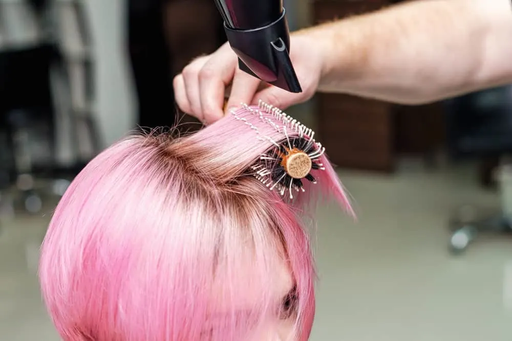 Professional colorist using gentle pressure to blow dry a client's hair after a hair coloring session.