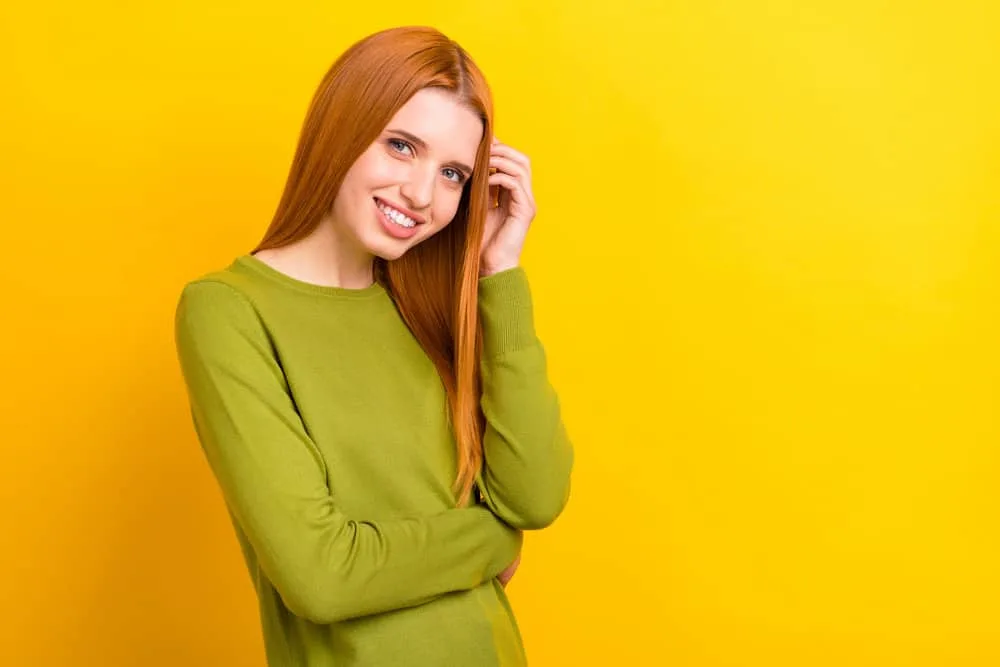 Young lady with red hair wearing thick hair extensions to make her completely straight limp locks look full.