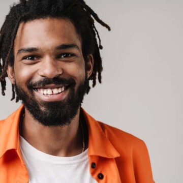 A young black guy with 4C natural hair with, a well-groomed appearance, dreadlocks, and wild beard growth.