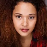 A young Hispanic woman wearing a DIY semi-permanent hair color on her naturally curly hair strands.