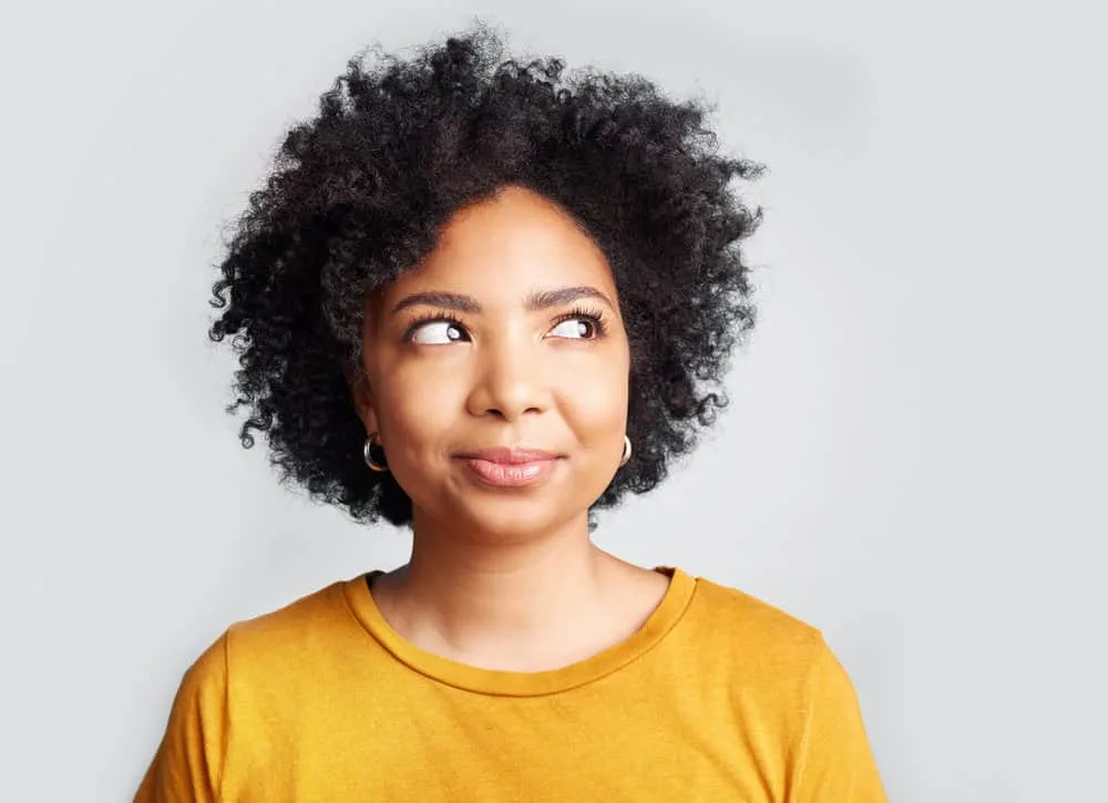 A young black female that has been applying hair gel to her curls for many years to mitigate hair breakage.