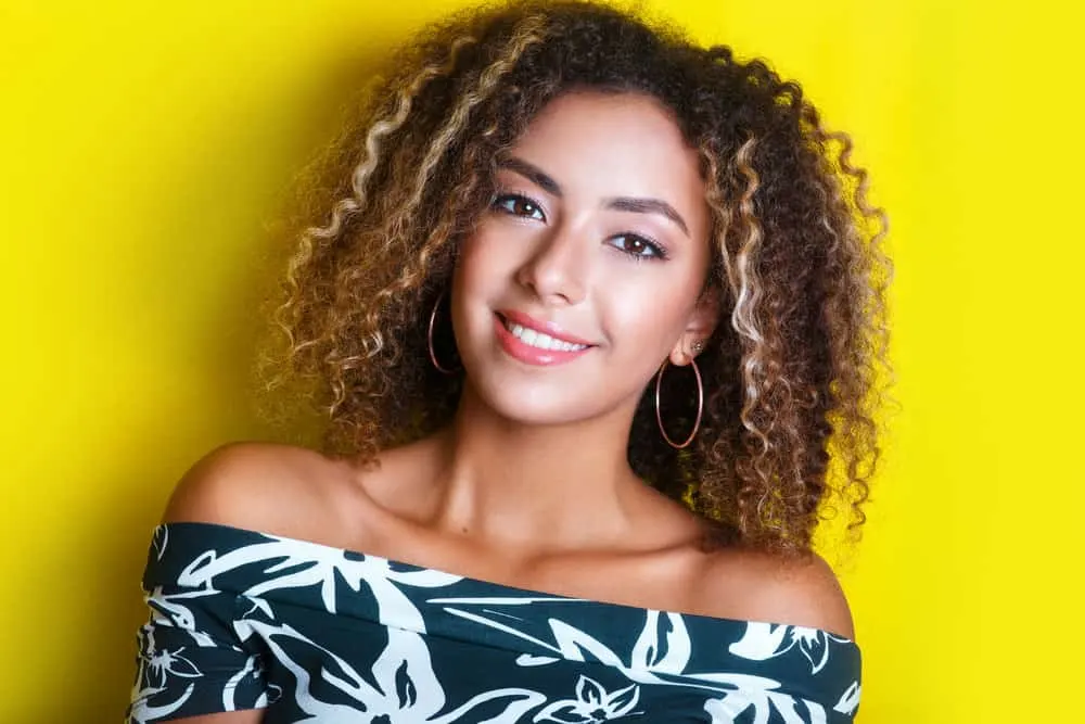 A young black girl wearing natural curls created with a freehand painting technique with a structured pattern.