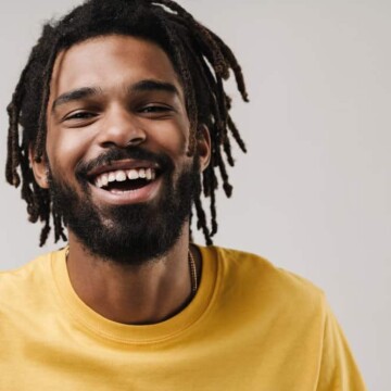 A young black guy wearing semi-freeform dreads with loose hair since his dreads were formed organically.