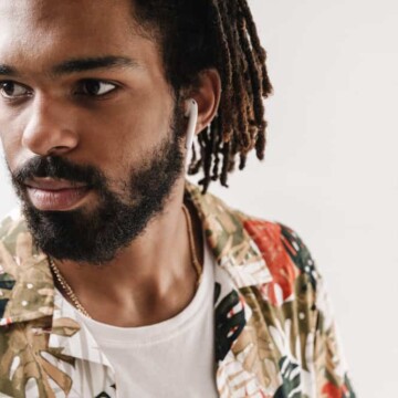 A young black man with thick locs on his 4B natural hair texture oiled with jojoba oil to encourage healthier locs.