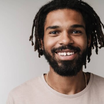 A young black man with healthy locs on 4B natural hair styled with tea tree oil, olive oil, and aloe vera juice.