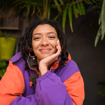 African American female with braided hair and loc extensions starting her dreadlock journey with two-strand twists.