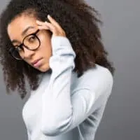 A young black girl with curly hair follicles colored with semi-permanent hair dye causing abnormal scalp irritation.