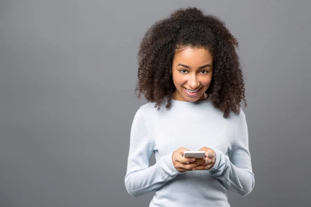 Cheerful young female researching how most chemical burns occur while using her brand new iPhone 14.