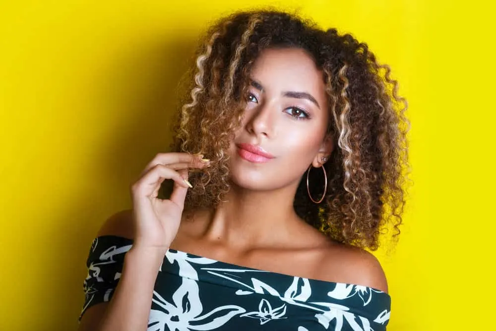 African American female with outside curls that are a few shades lighter with deeper natural hair colors underneath.