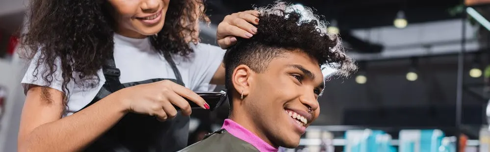 A black man getting either a cheap or free haircut at his favorite hair salon in her local community.