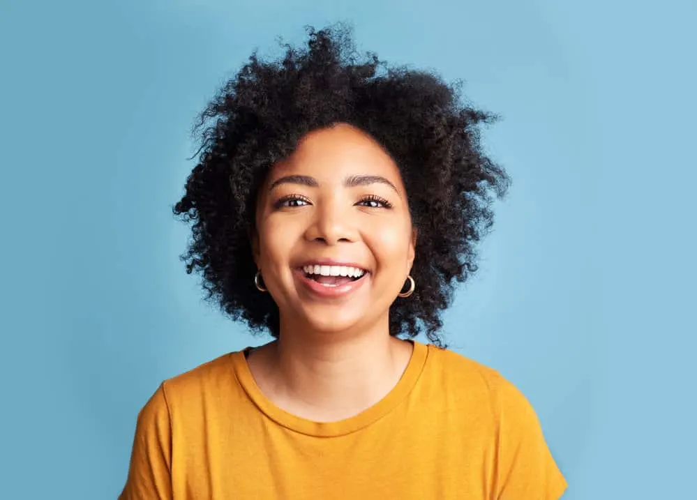 An attractive woman with should length hair growth uses Curly Girl hair styling products like aloe vera gel.