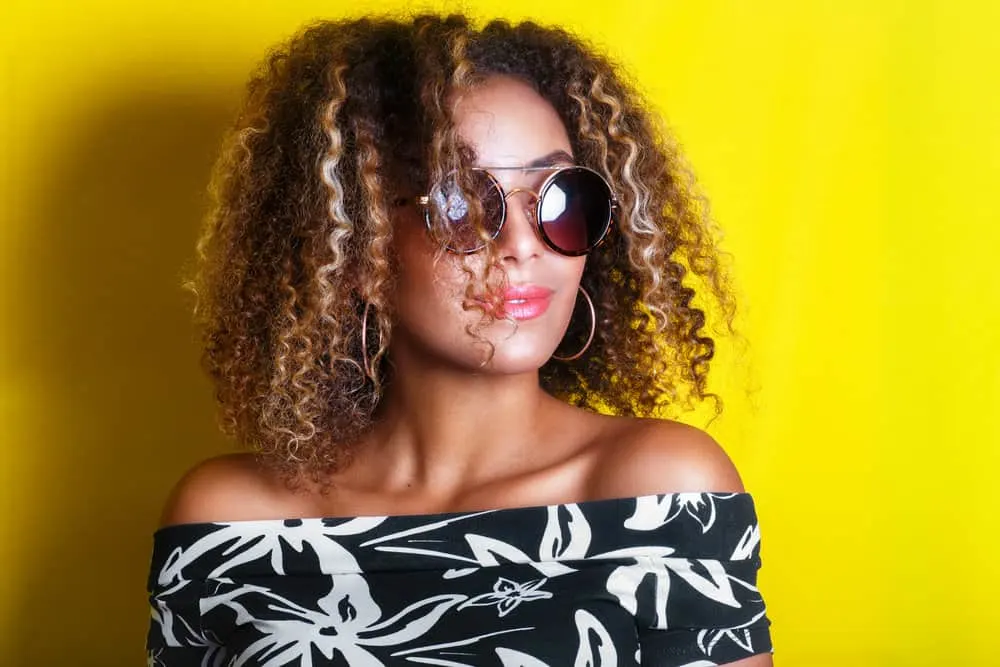 A lady wearing natural curls created with a highlighting process that used aluminum foil during the salon appointment.