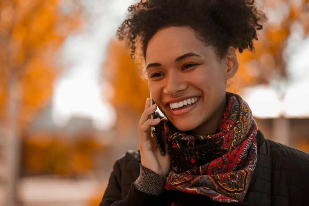 A cute black female with a definite curl pattern is wearing a colorful scarf according to a particular hair typing system.