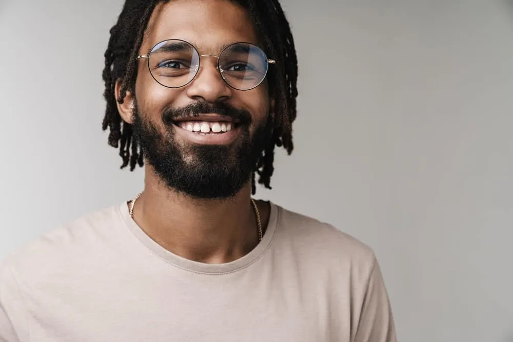 A black male that has healthy hair styled with sweet almond oil and vitamin E oil is showing off his healthy locs.