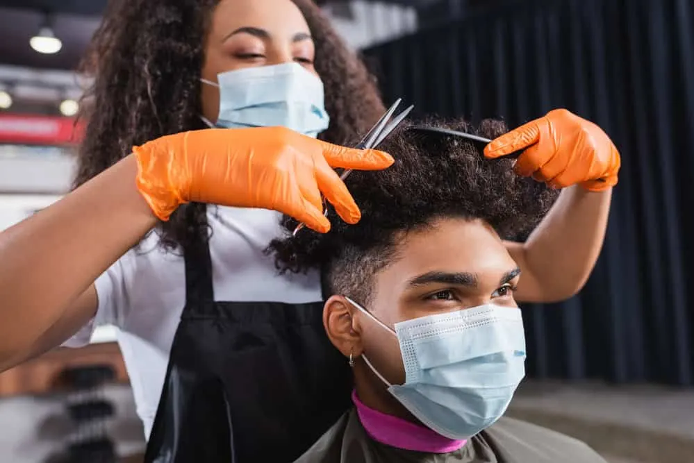 A black man with curly hair has less hair than many females, although the stylist is using the same process.