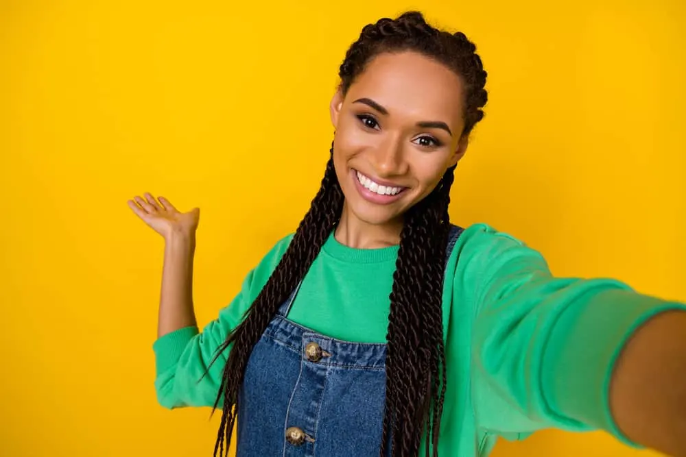 A pretty young black woman with a combo of curly and coily hair types in a braided protective hairstyle.