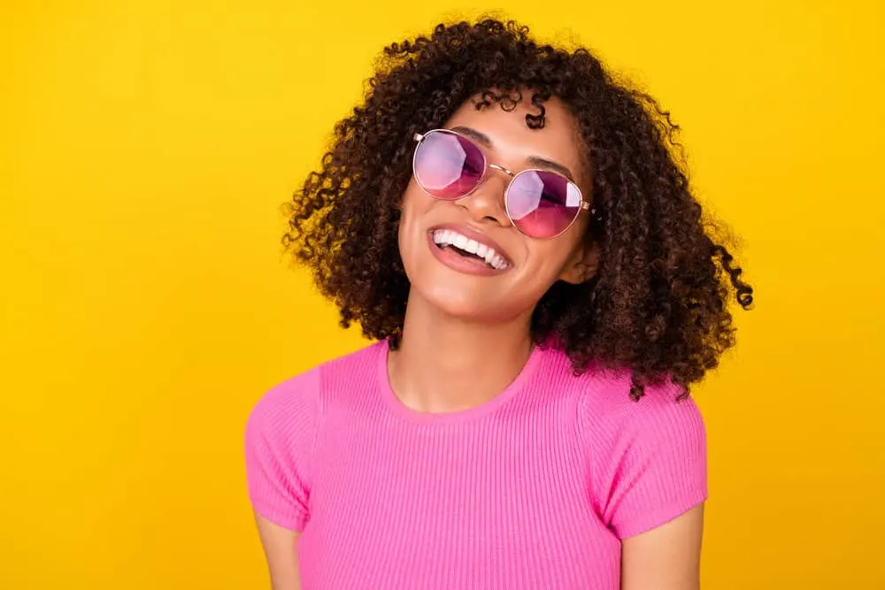 A happy black lady with soft, silky smooth, frizz-free natural curls that will blow dry her hair before wash-n-go styles.