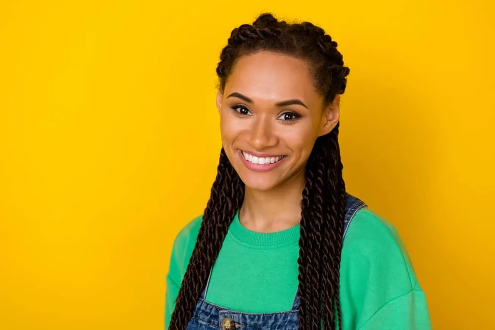 A lovely young female with fine hair wearing a mid-back length braided hair style with a green sweatshirt.