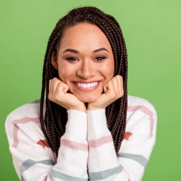 A cheerful young female with synthetic hair extensions combined with her real hair moisturized with coconut oil.