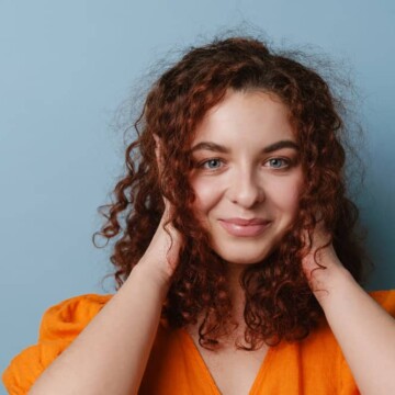 A naturally curly girl with healthy hair wearing her frizzy hair in a standard style created with a wide tooth comb.