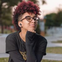 A Latin woman with a sensitive scalp and curly hair follicles after bleaching her hair for a red hair dyeing session.