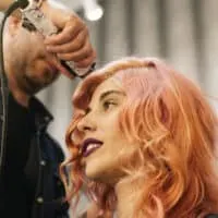 A beautiful woman is getting her hair done by a hair stylist at a cosmetology school at a high-end salon.