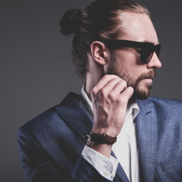 A handsome white guy wearing a man bun hairstyle in a half-up top-knot style secured with elastic band hair ties.