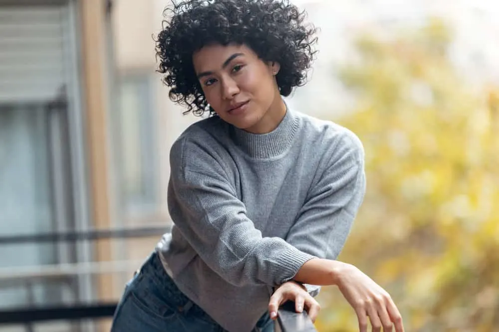 A mixed-race black girl with natural hair styled her curls with a leave-in conditioner with moisturizing properties.