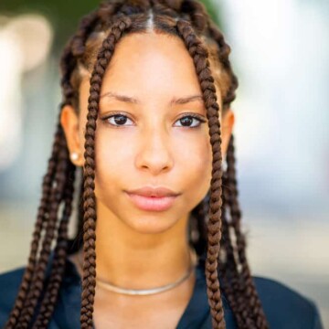 A cute black female is wearing Fulani brands on her 4A natural hair type, which is a great protective style for summer.