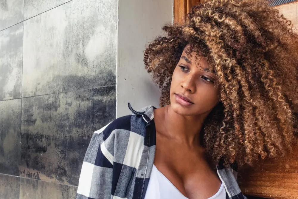 A black girl with medium hair about half an inch past her collarbone wearing her naturally coarse hair fluffy style.