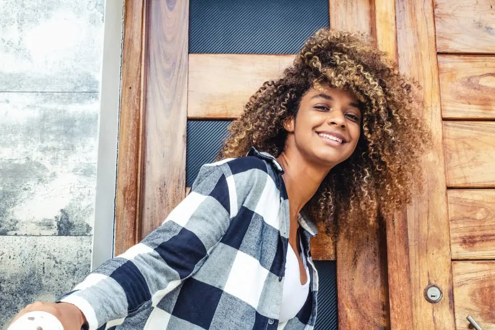 A woman with coily hair wearing her natural texture gets more frequent haircuts to maintain a specific shape.