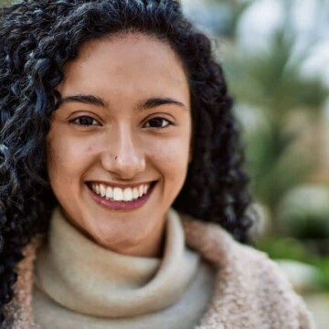 A cute black girl with long hair wearing a wolf cut in a v-shape on type 3 curly hair showing more face on the left side.