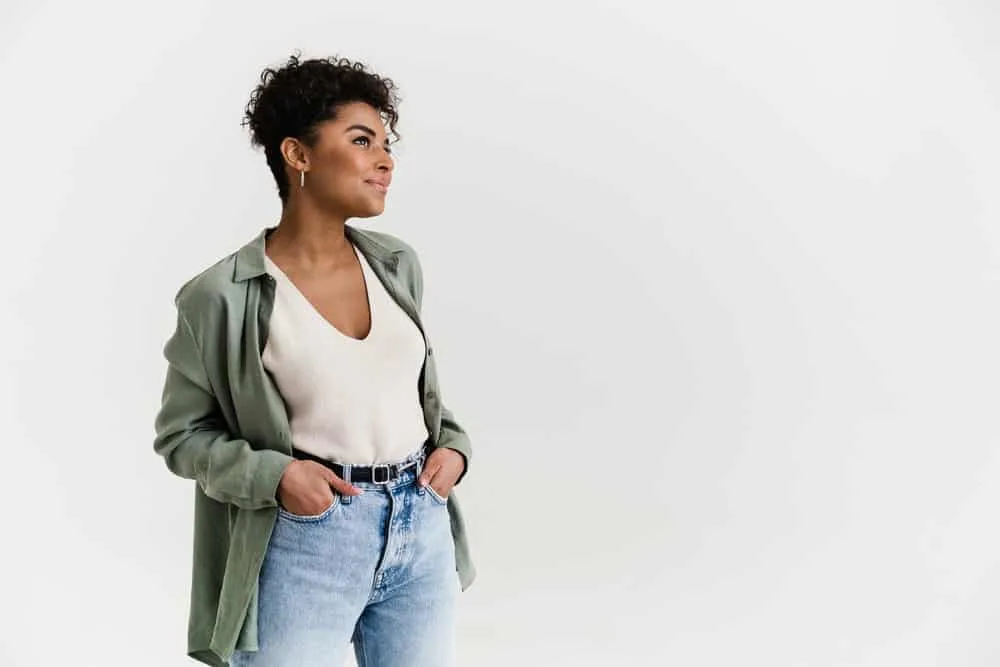 A young black woman with hair dye stains on her shirt after recently dyeing her curly hair a dark brown color.