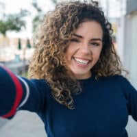 A young Latin female with beautiful curly hair is wondering why aging curly hair changes for many women.