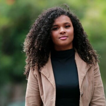 A confident black female with towel-dried hair used a conditioning treatment to build healthier hair strands.