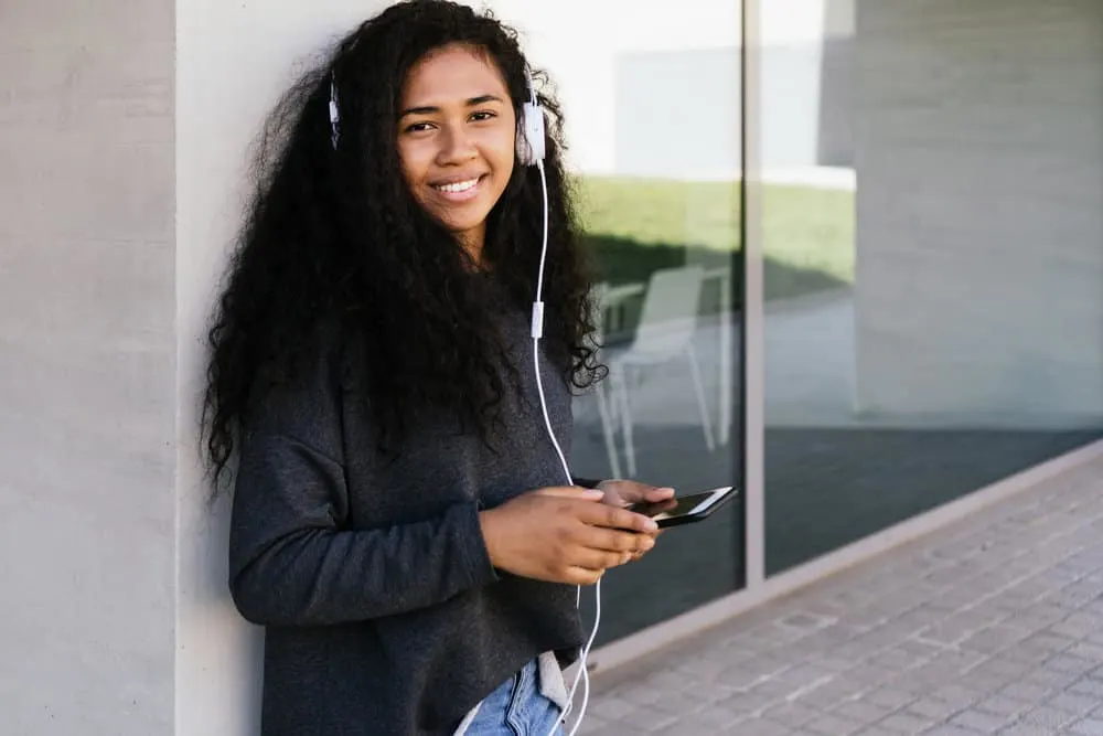 A black woman with huge fluffy curls keeps her hair moisturized and curls healthy with a daily curly girl hair routine.