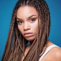 A young black girl with a gorgeous hairstyle wearing thin braids on naturally textured long hair with hair cuffs.