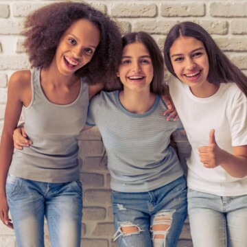 Three friends - one with natural curls following the big hair trend, one with long hair, and one with protective hair spray.