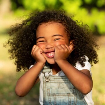 An adorable little girl with long hair has a beautiful hairstyle without any hair accessories or thick braids.