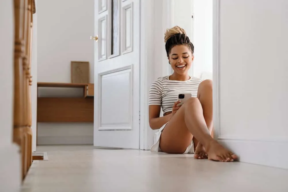 A lady is sitting on the floor at home watching YouTube videos on how to start microlocs using the interlocking method.