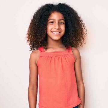 A cute little black princess with long hair wearing one of the most popular black girl hairstyles for curly thick hair.