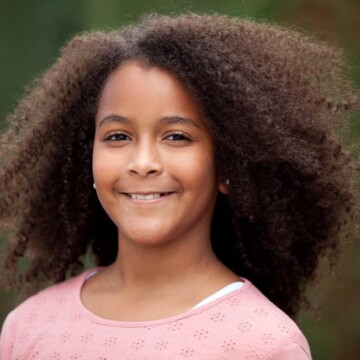 A beautiful 12-year-old with thick hair showing off her natural curls wearing a wash-n-go on her long curly hair.