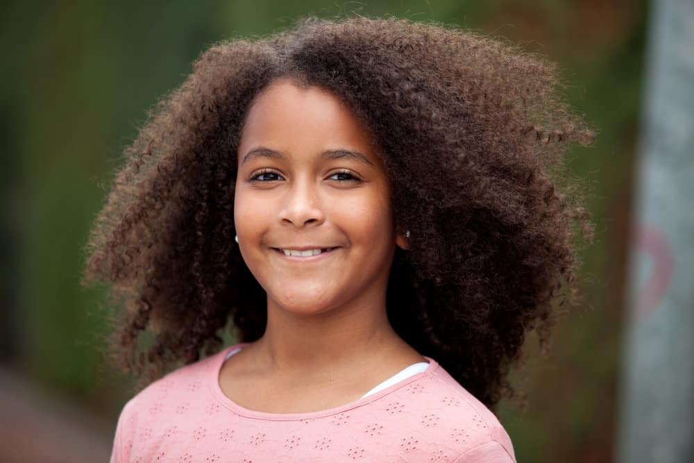 A beautiful 12-year-old with thick hair showing off her natural curls wearing a wash-n-go on her long curly hair.