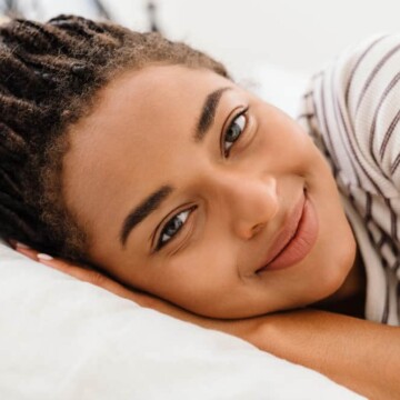 A young black woman with a type 4 hair type has braids with a defined grid pattern on an asymmetrical head shape.